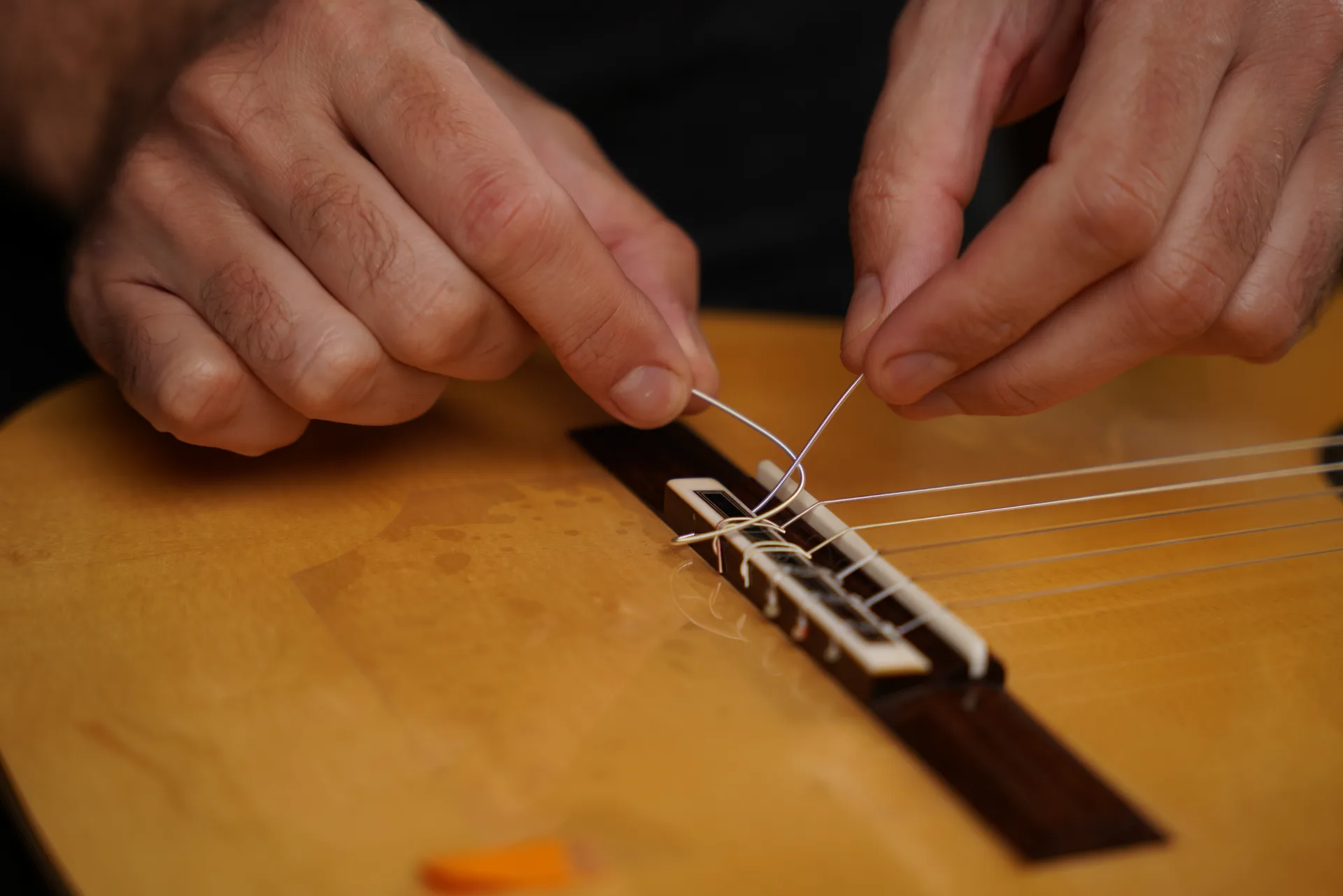 Pass the wound bass string through the bridge hole, then form a loop