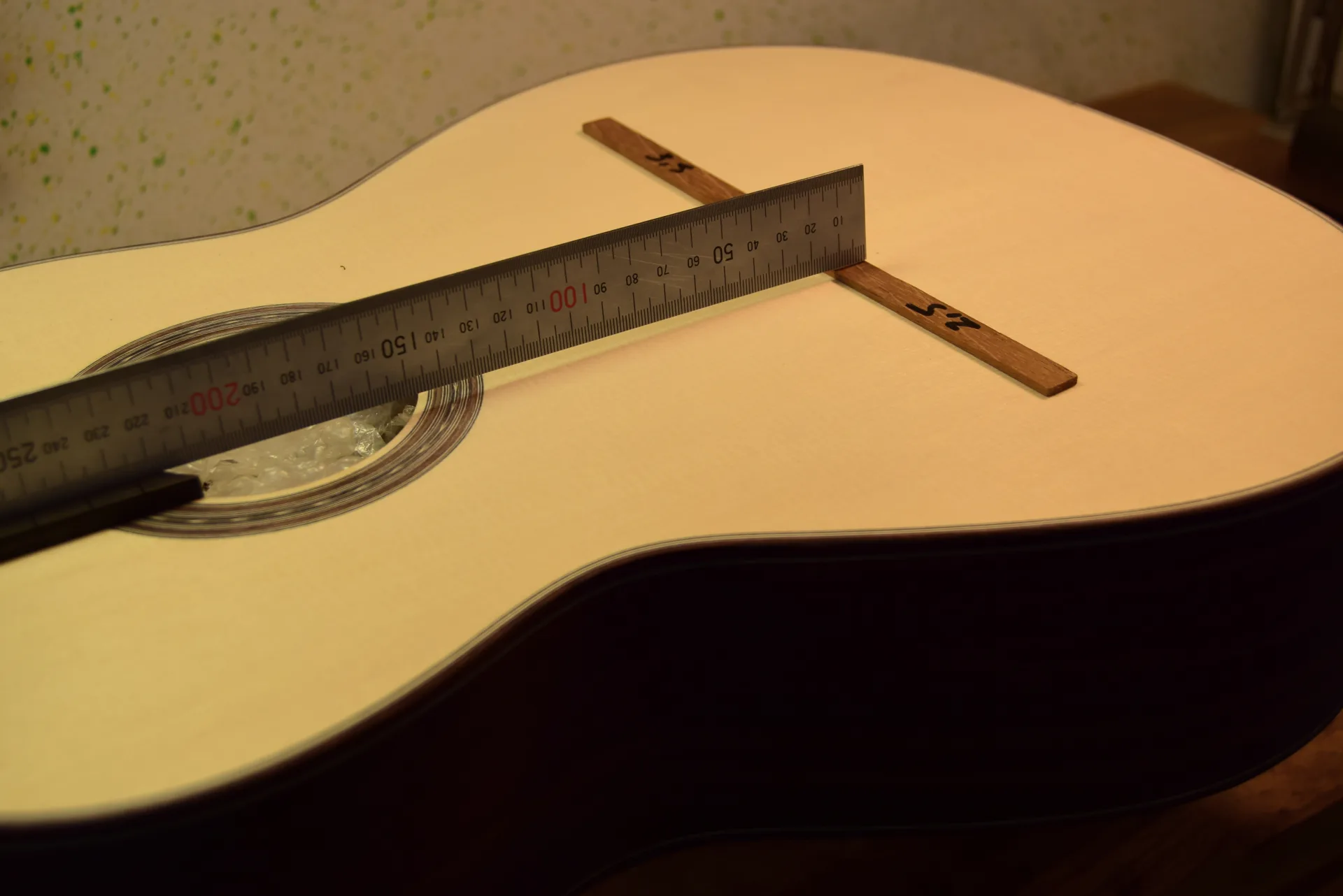 Setting neck angle without strings — a straightedge on the fingerboard measures the gap at the future bridge position