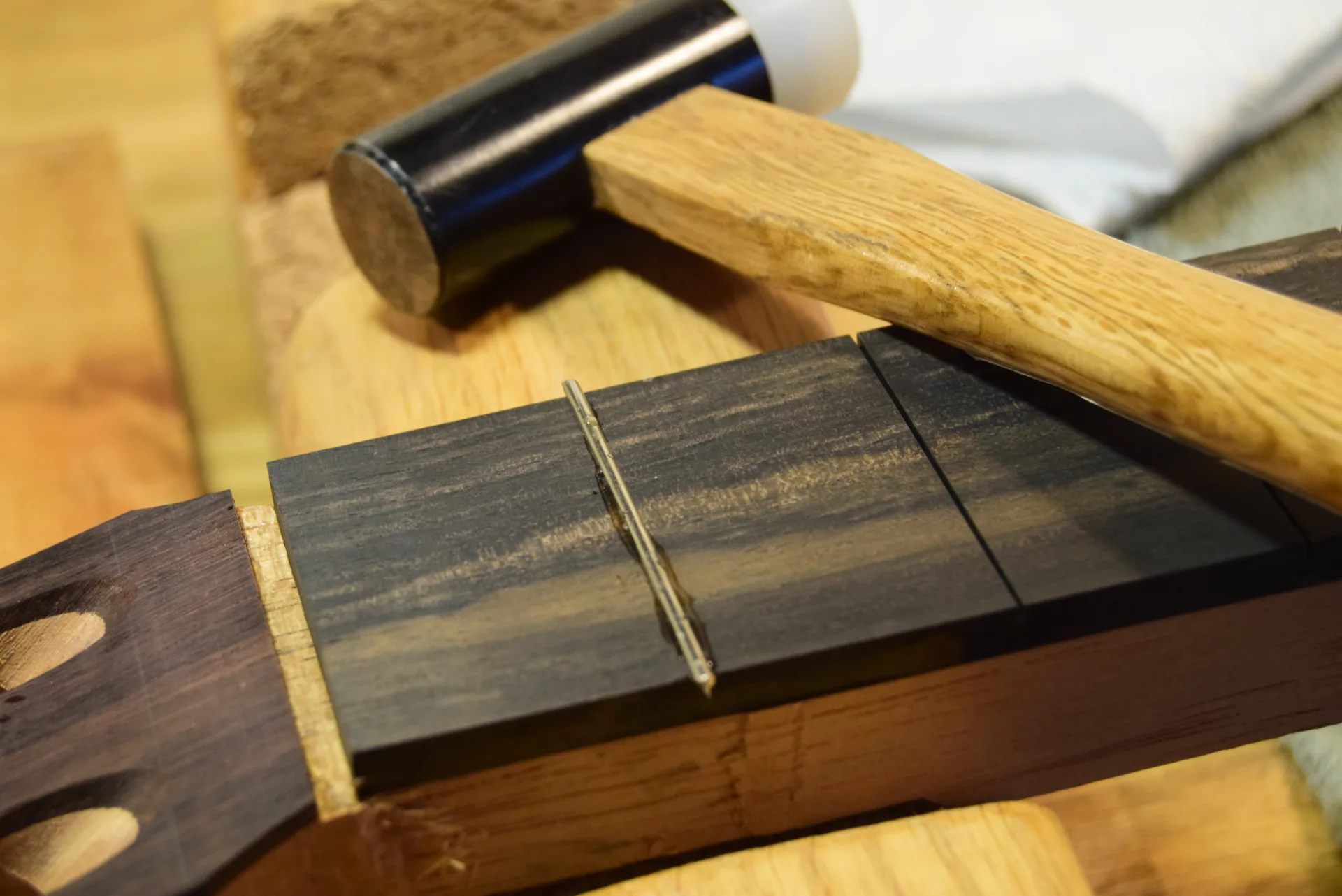 Installing frets with a plastic-faced hammer and hot hide glue to secure the fret wire