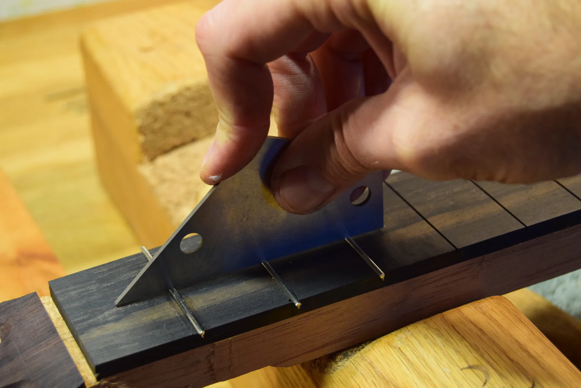 Checking fret level with a fret rocker — if it rocks, the middle fret is too high and needs another tap